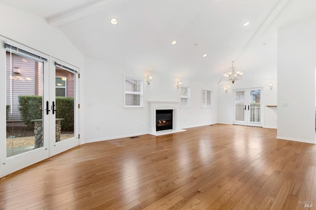 unfurnished living room with light hardwood / wood-style flooring, high vaulted ceiling, beamed ceiling, french doors, and a chandelier