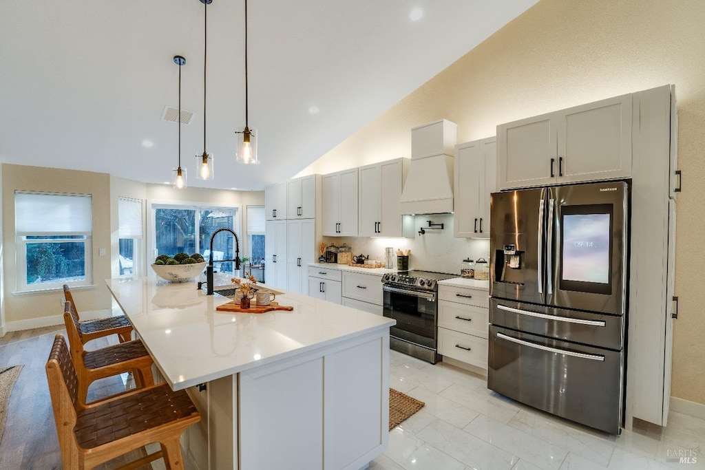 kitchen featuring premium range hood, a breakfast bar, sink, appliances with stainless steel finishes, and a kitchen island with sink