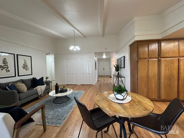 dining area featuring a chandelier, beam ceiling, and light hardwood / wood-style flooring