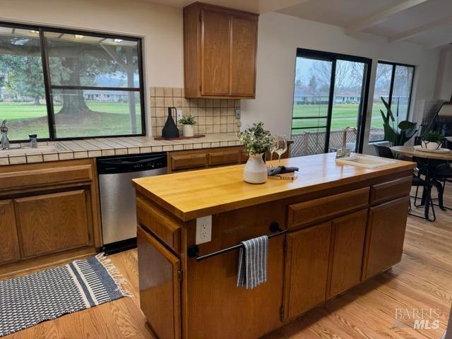 kitchen with sink, light hardwood / wood-style flooring, dishwasher, tasteful backsplash, and beamed ceiling