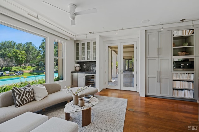 living room with a healthy amount of sunlight, wet bar, beverage cooler, and dark hardwood / wood-style floors