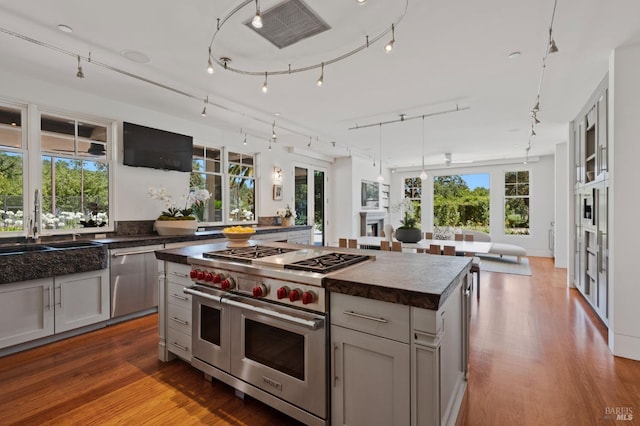 kitchen with gray cabinetry, hardwood / wood-style flooring, a center island, and appliances with stainless steel finishes