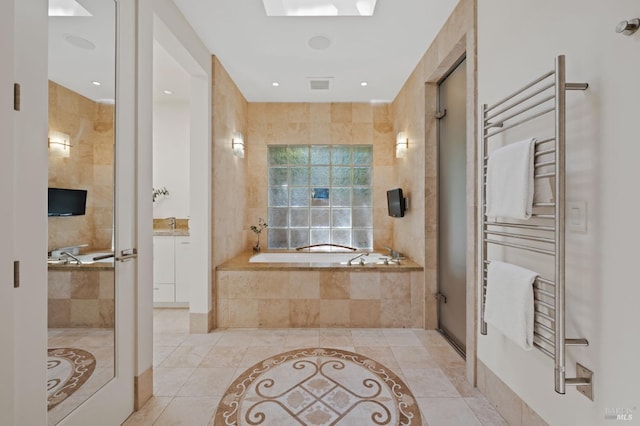 bathroom with tiled tub, radiator, tile walls, and tile patterned floors