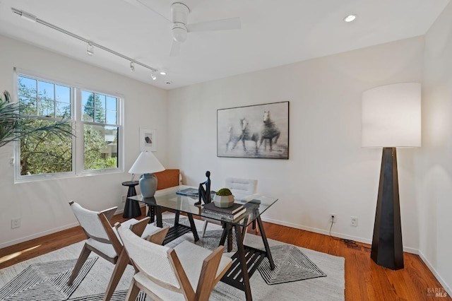 home office with wood-type flooring, rail lighting, and ceiling fan