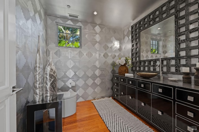 interior space featuring vanity, hardwood / wood-style floors, tile walls, and toilet