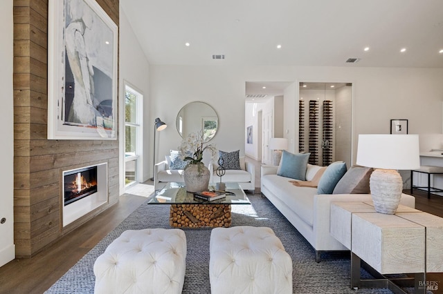 living room with dark wood-type flooring and a large fireplace