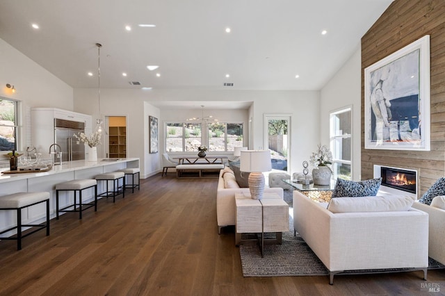 living room with a notable chandelier, dark wood-type flooring, vaulted ceiling, and sink