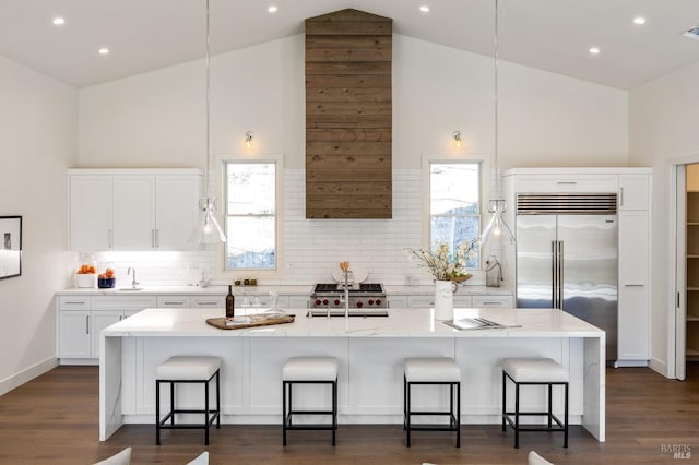 kitchen featuring stainless steel built in refrigerator, an island with sink, and a breakfast bar area