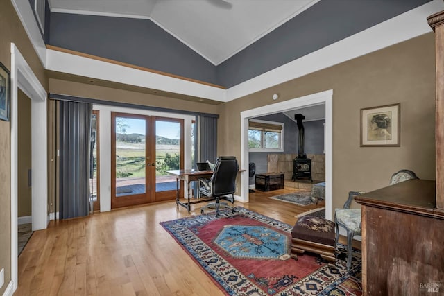 home office featuring french doors, hardwood / wood-style flooring, high vaulted ceiling, and a wood stove