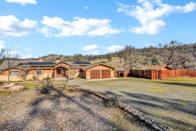 single story home with a garage and solar panels