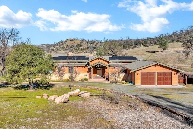 view of front facade featuring a garage, a front yard, and solar panels