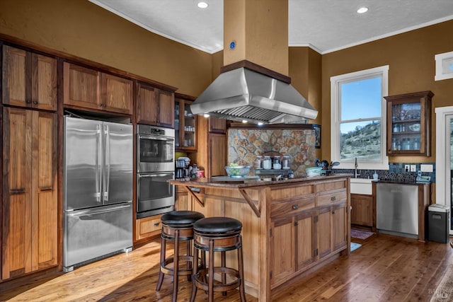 kitchen featuring a kitchen bar, a center island, island exhaust hood, stainless steel appliances, and decorative backsplash