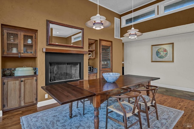 dining area with a high ceiling, ornamental molding, dark hardwood / wood-style floors, and built in shelves