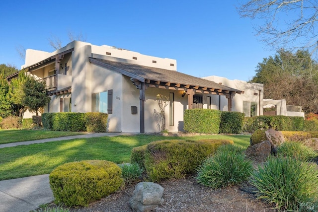 adobe home with a balcony and a front lawn