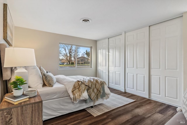 bedroom with dark hardwood / wood-style flooring and two closets