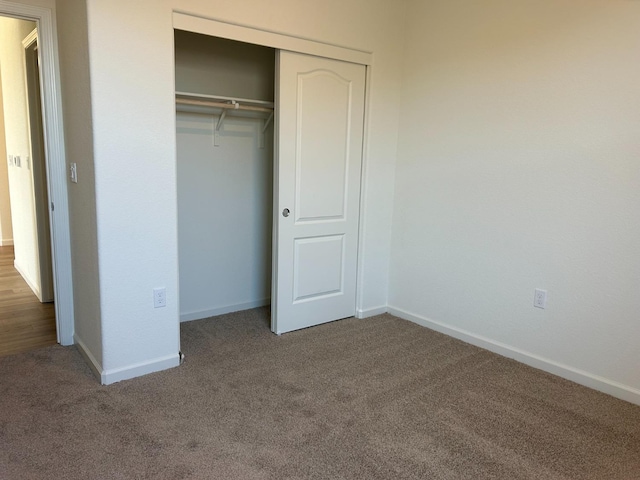 unfurnished bedroom featuring carpet, baseboards, and a closet