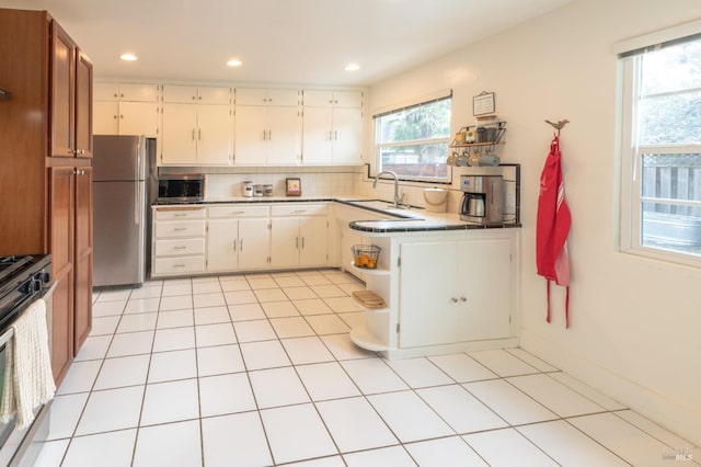 kitchen featuring sink, tasteful backsplash, white cabinetry, light tile patterned floors, and appliances with stainless steel finishes