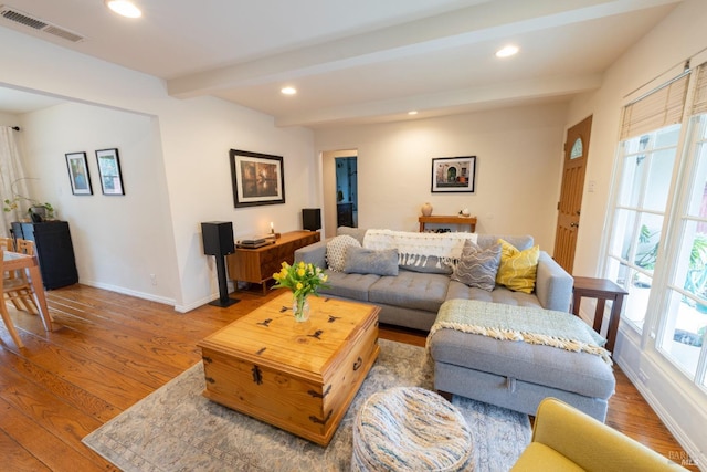 living room with hardwood / wood-style floors, beam ceiling, and a healthy amount of sunlight