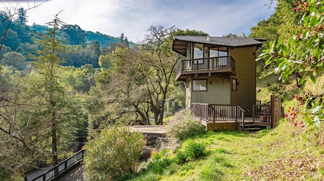 rear view of house featuring a wooden deck and a balcony