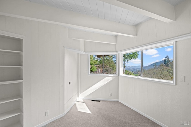 unfurnished bedroom featuring carpet floors, wood walls, and beamed ceiling