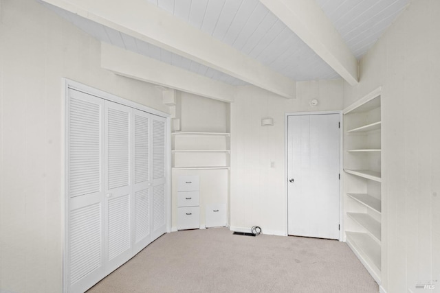 unfurnished bedroom featuring carpet floors, beam ceiling, and a closet