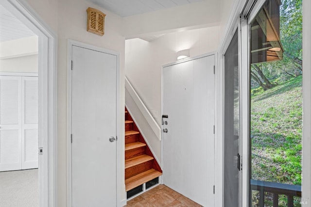 entryway with light tile patterned floors, plenty of natural light, and stairs