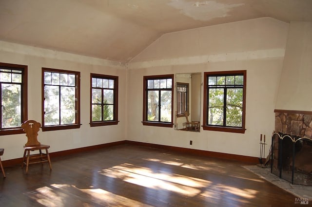 living room featuring lofted ceiling, dark hardwood / wood-style floors, a wealth of natural light, and a stone fireplace