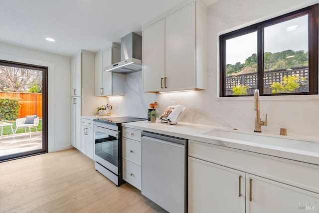 kitchen featuring white cabinetry, appliances with stainless steel finishes, wall chimney exhaust hood, and sink