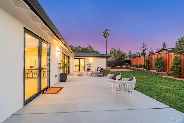 patio terrace at dusk featuring outdoor lounge area and a yard