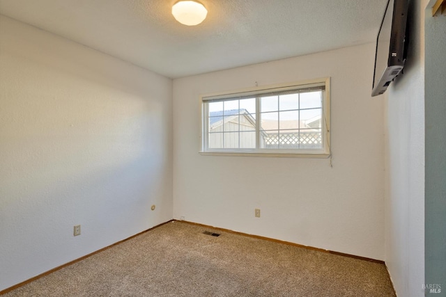 empty room featuring carpet, a wall mounted air conditioner, and a textured ceiling