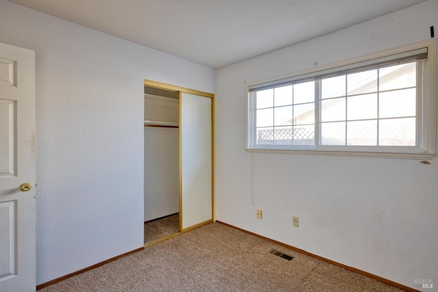 unfurnished bedroom with light colored carpet and a closet