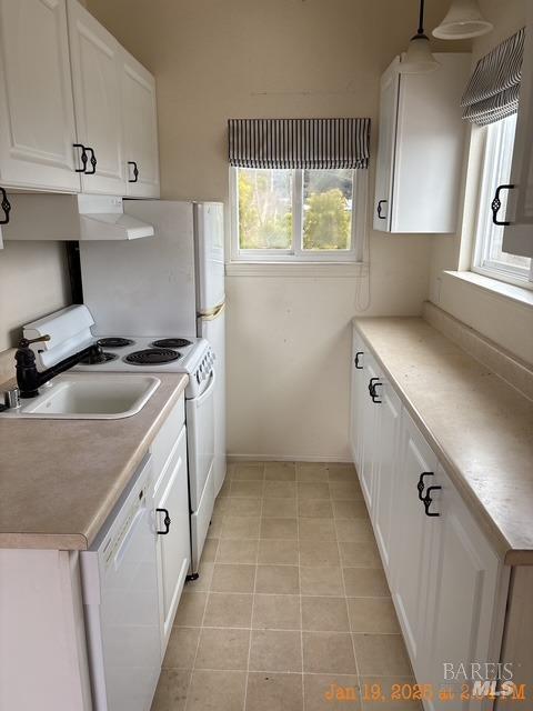 kitchen with white appliances, decorative light fixtures, light tile patterned floors, and white cabinets