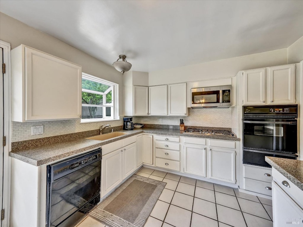 kitchen with backsplash, a sink, a warming drawer, light tile patterned floors, and black appliances
