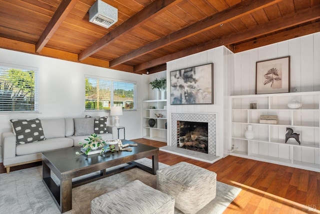 living room featuring a tiled fireplace, hardwood / wood-style floors, wood ceiling, and beam ceiling