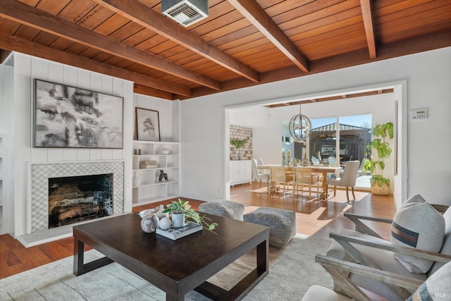 living room with beamed ceiling, wood-type flooring, a fireplace, and wooden ceiling