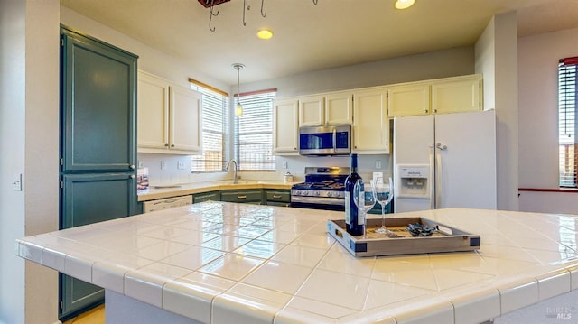 kitchen featuring pendant lighting, tile countertops, stainless steel appliances, and green cabinets