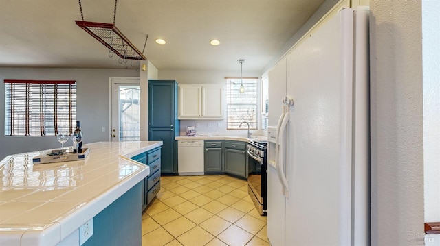 kitchen featuring decorative light fixtures, tile countertops, light tile patterned floors, white appliances, and white cabinets