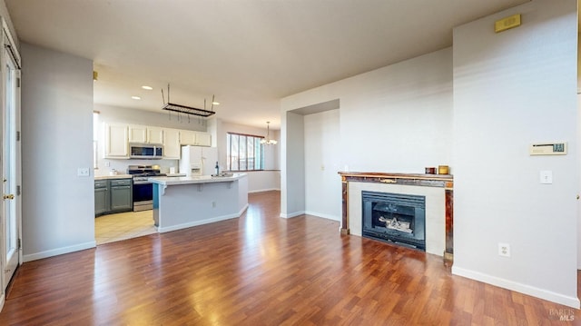 unfurnished living room with sink, light hardwood / wood-style floors, and a notable chandelier