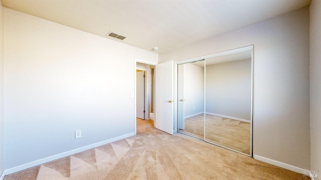 unfurnished bedroom with a closet and light carpet