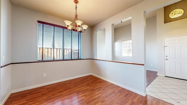 spare room with an inviting chandelier and light hardwood / wood-style flooring