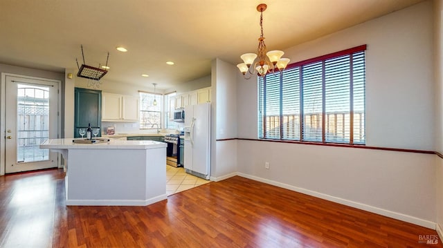 kitchen featuring white cabinetry, decorative light fixtures, appliances with stainless steel finishes, a healthy amount of sunlight, and light hardwood / wood-style floors