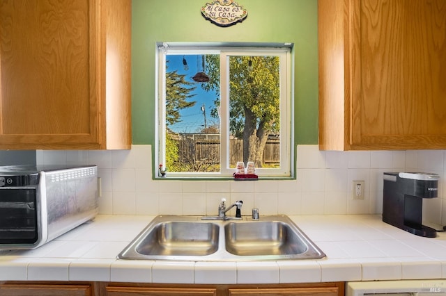 kitchen featuring dishwasher, sink, tile countertops, and backsplash