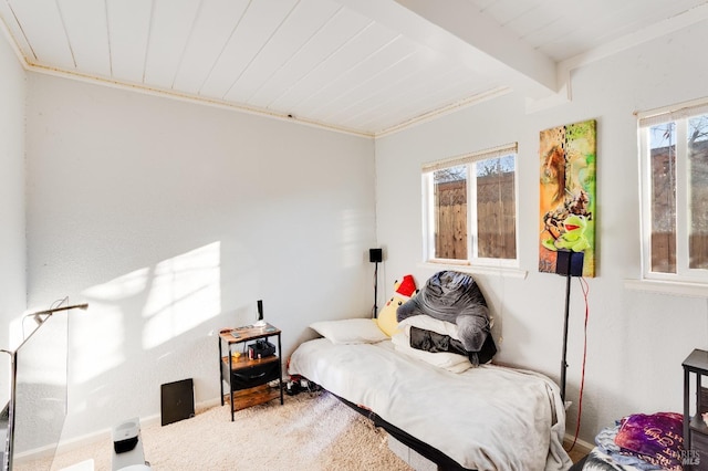 bedroom with crown molding, beam ceiling, and carpet