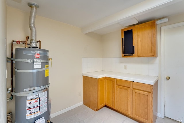 kitchen featuring tasteful backsplash, light tile patterned floors, tile counters, and water heater