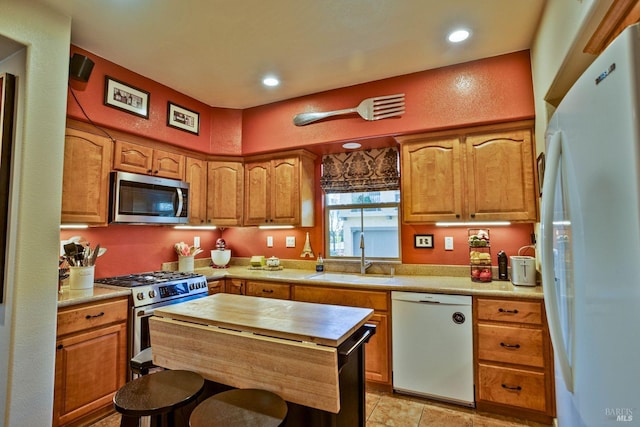 kitchen with appliances with stainless steel finishes, sink, and light tile patterned floors