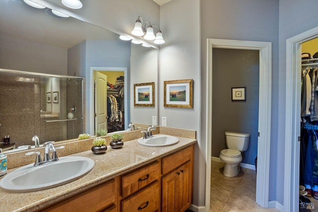 bathroom with tile patterned flooring, vanity, a shower with door, and toilet