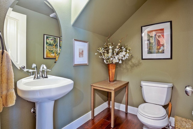 bathroom featuring wood-type flooring, toilet, and vaulted ceiling