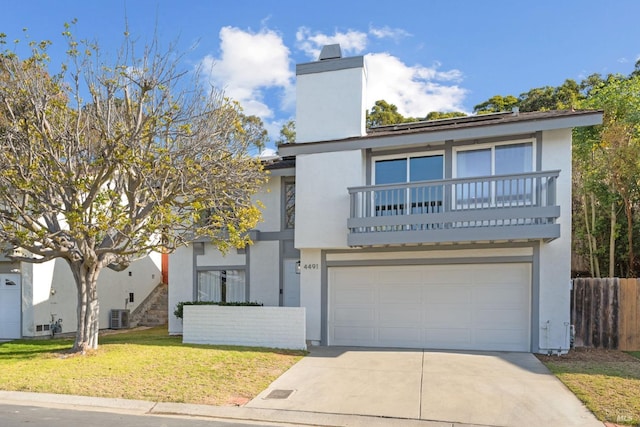 view of front of property featuring cooling unit, a balcony, a garage, and a front lawn