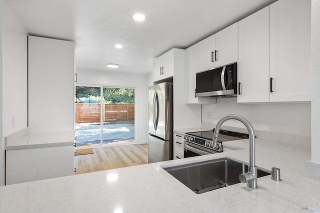 kitchen with white cabinetry, sink, light wood-type flooring, and appliances with stainless steel finishes