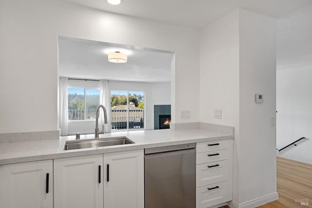 kitchen featuring sink, light hardwood / wood-style flooring, stainless steel dishwasher, and white cabinets